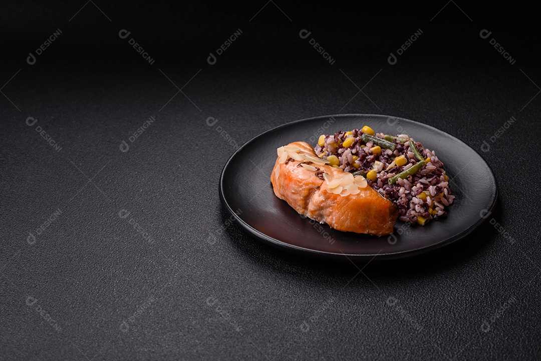 Um pedaço de salmão cozido com arroz, brócolis, sal e especiarias em um fundo de concreto escuro