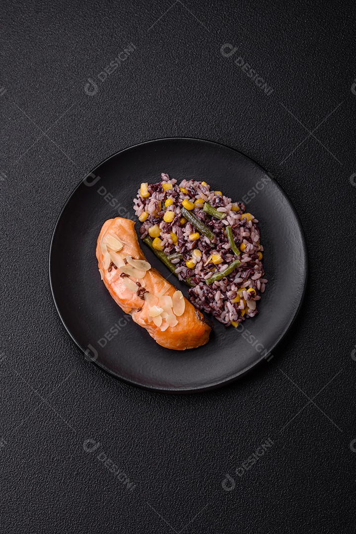 Um pedaço de salmão cozido com arroz, brócolis, sal e especiarias em um fundo de concreto escuro