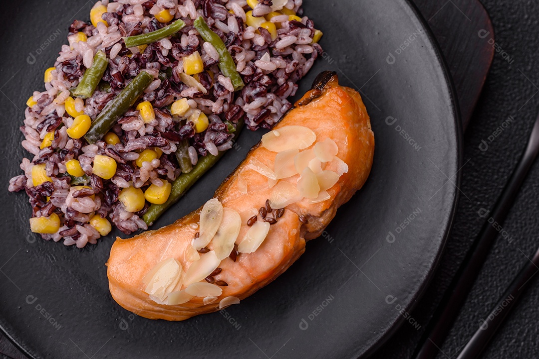 Um pedaço de salmão cozido com arroz, brócolis, sal e especiarias em um fundo de concreto escuro