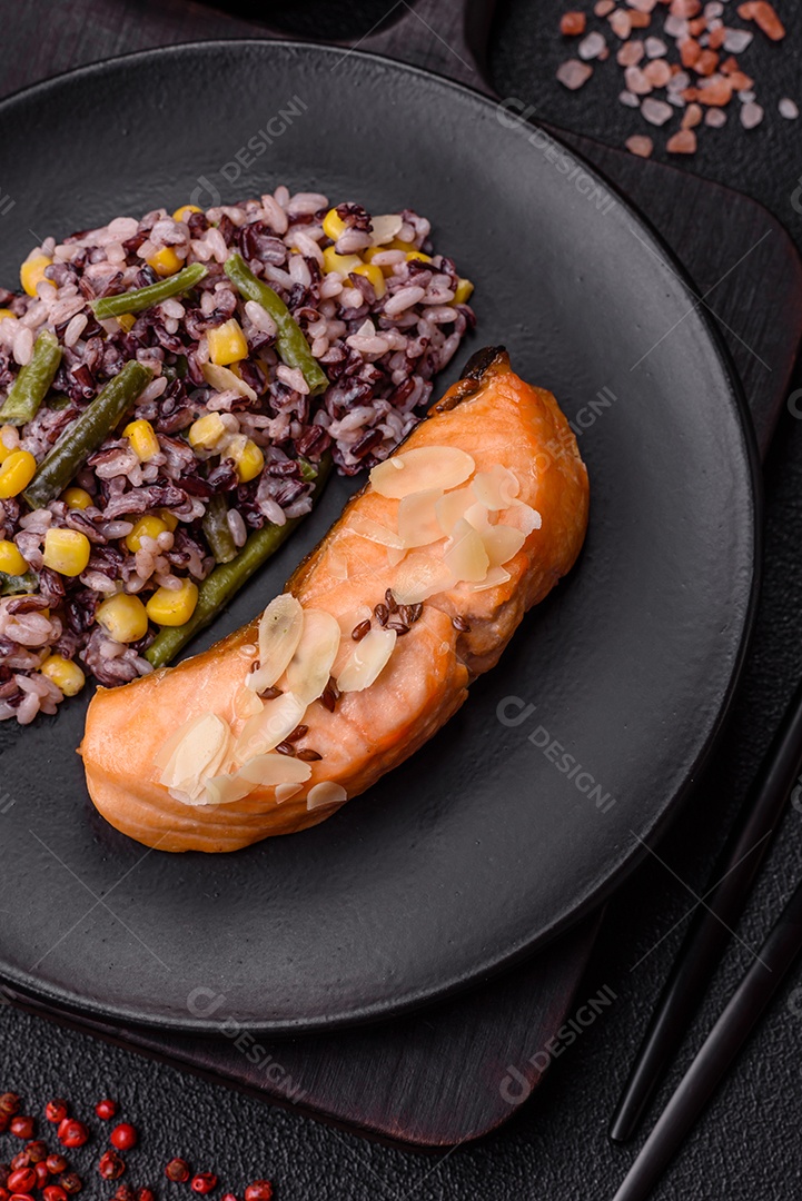 Um pedaço de salmão cozido com arroz, brócolis, sal e especiarias em um fundo de concreto escuro