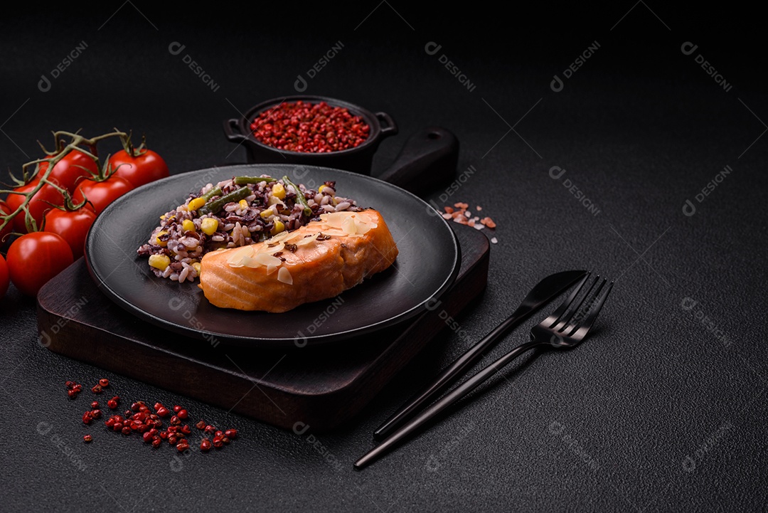 Um pedaço de salmão cozido com arroz, brócolis, sal e especiarias em um fundo de concreto escuro