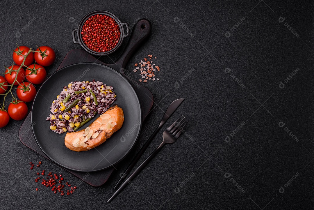 Um pedaço de salmão cozido com arroz, brócolis, sal e especiarias em um fundo de concreto escuro