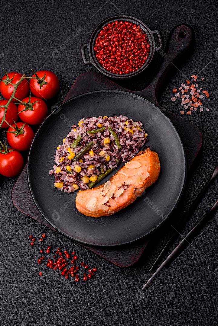 Um pedaço de salmão cozido com arroz, brócolis, sal e especiarias em um fundo de concreto escuro