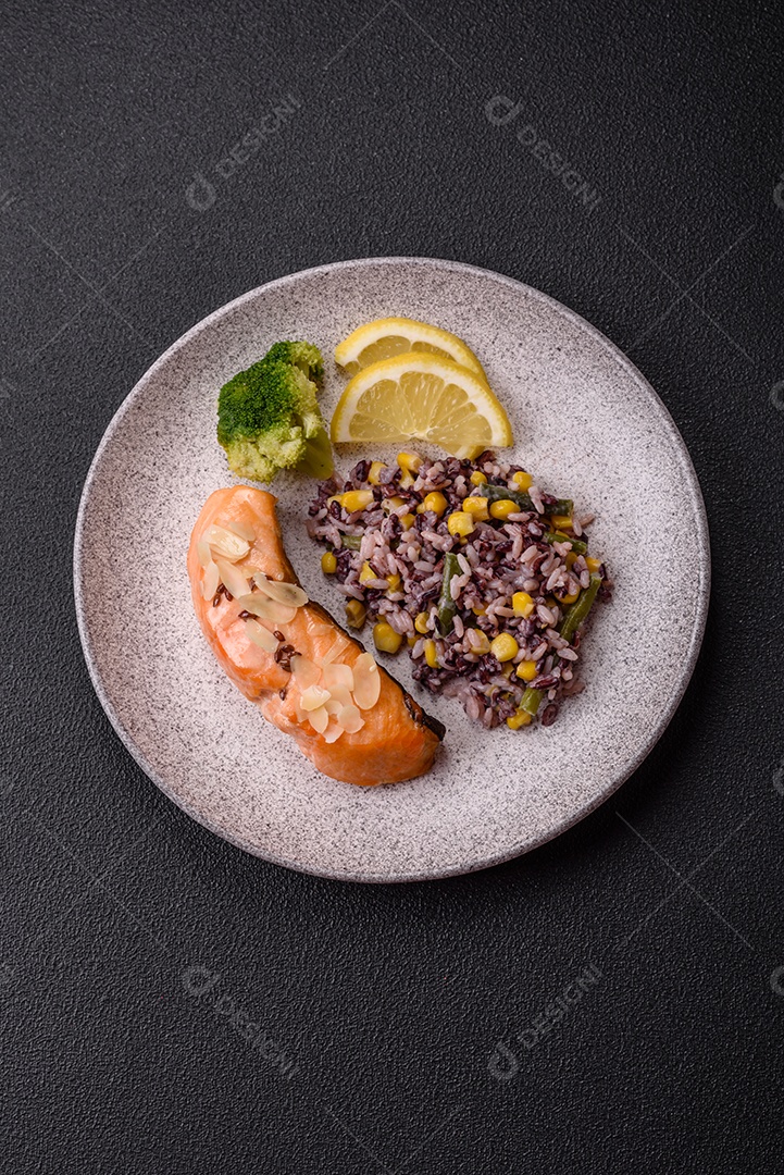 Um pedaço de salmão cozido com arroz, brócolis, sal e especiarias em um fundo de concreto escuro