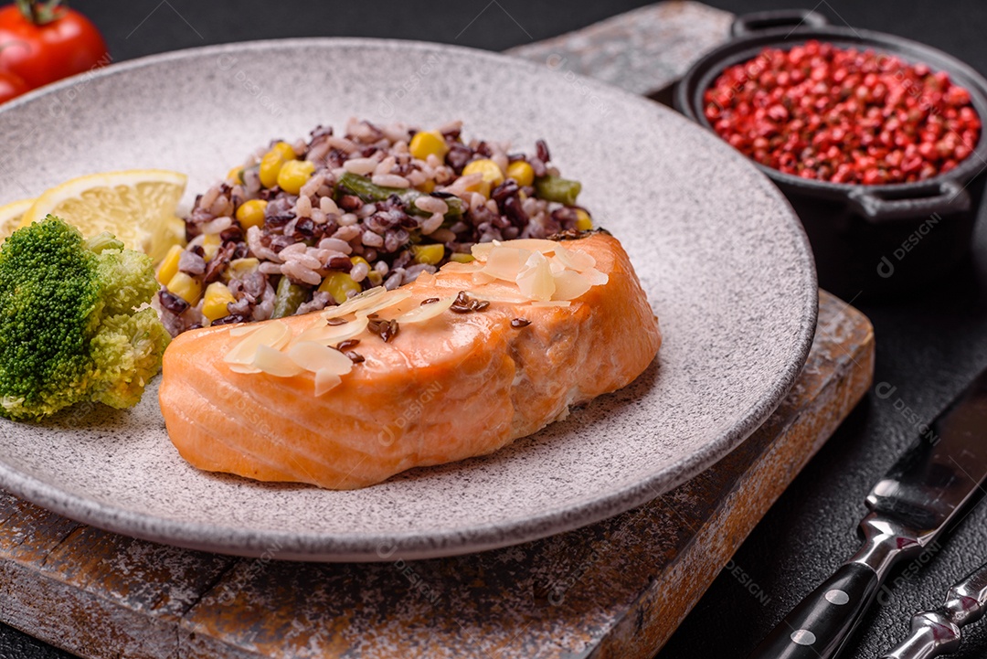 Um pedaço de salmão cozido com arroz, brócolis, sal e especiarias em um fundo de concreto escuro