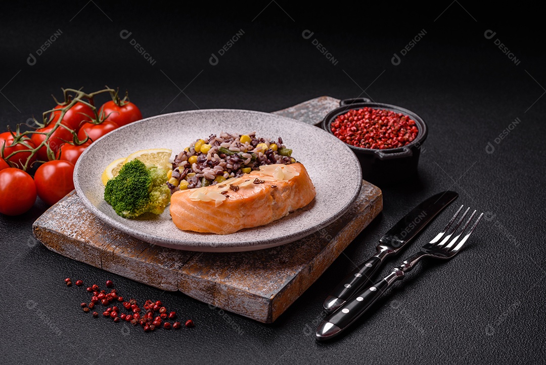 Um pedaço de salmão cozido com arroz, brócolis, sal e especiarias em um fundo de concreto escuro