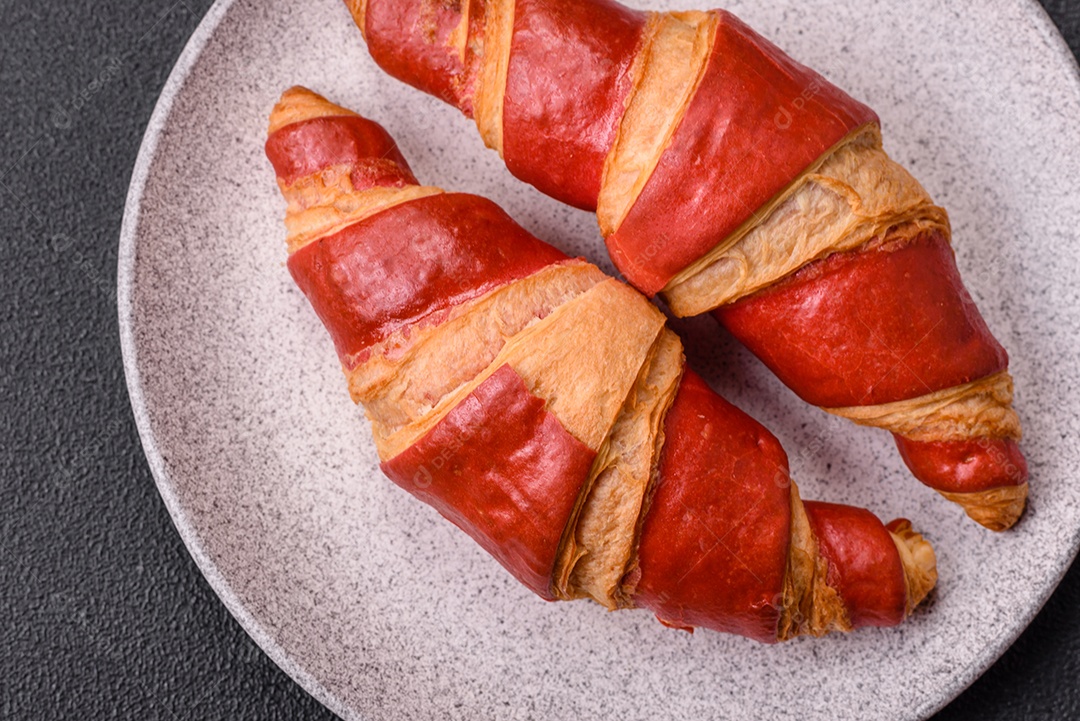 Croissant assado sobre prato em uma mesa de concreto