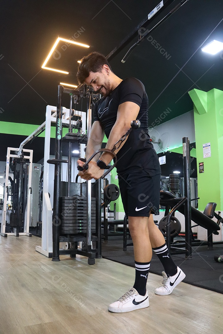 Belo homem fazendo exercicíos sobre uma academia