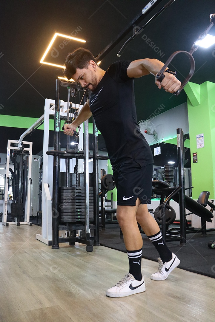 Belo homem fazendo exercicíos sobre uma academia
