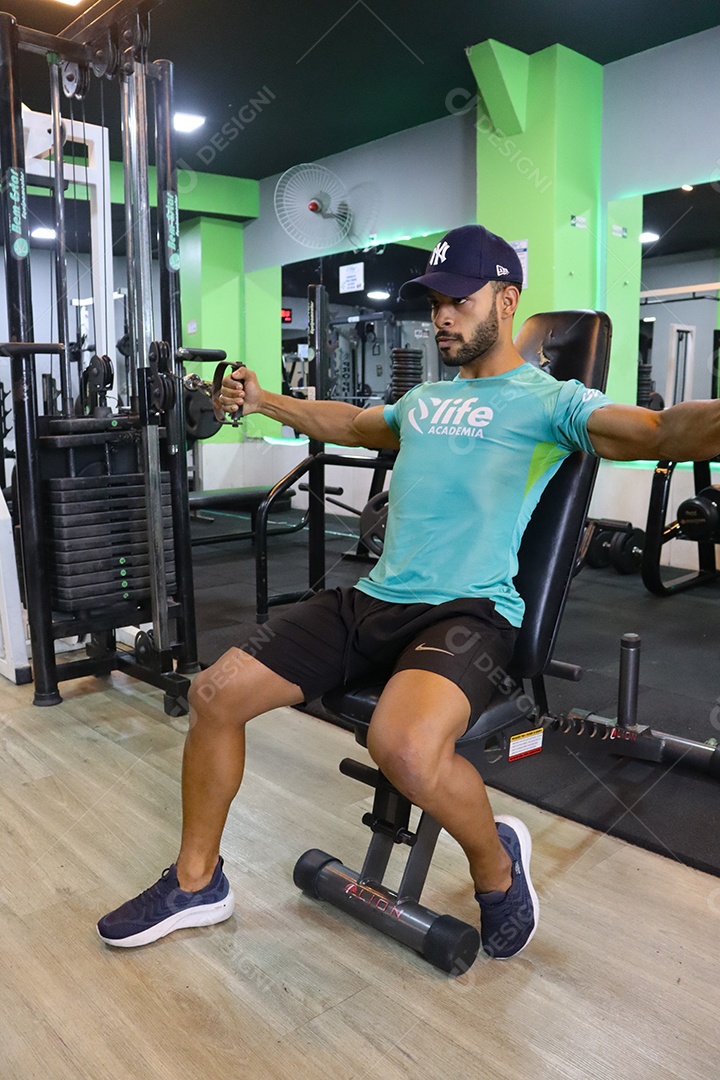 Belo homem fazendo exercicíos sobre uma academia