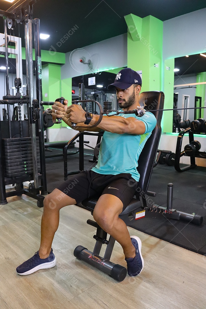 Belo homem fazendo exercicíos sobre uma academia