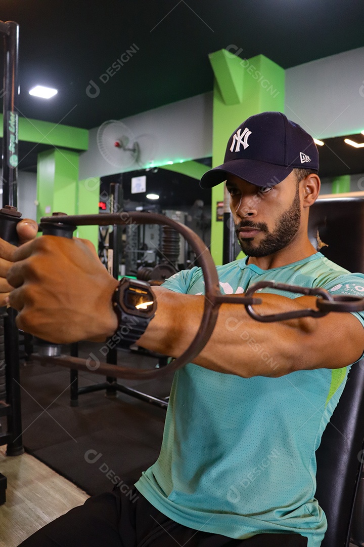 Belo homem fazendo exercicíos sobre uma academia