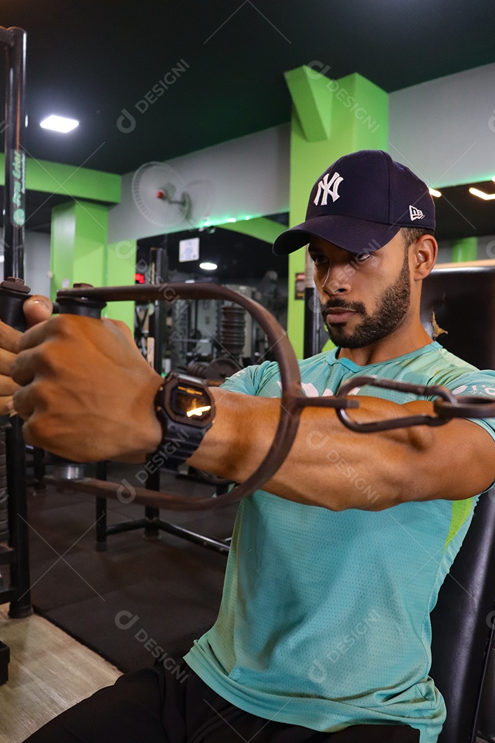 Belo homem fazendo exercicíos sobre uma academia