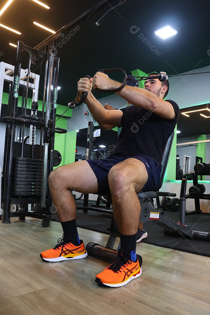 Belo personal trainer ajudando homem executar exercícios sobre uma academia