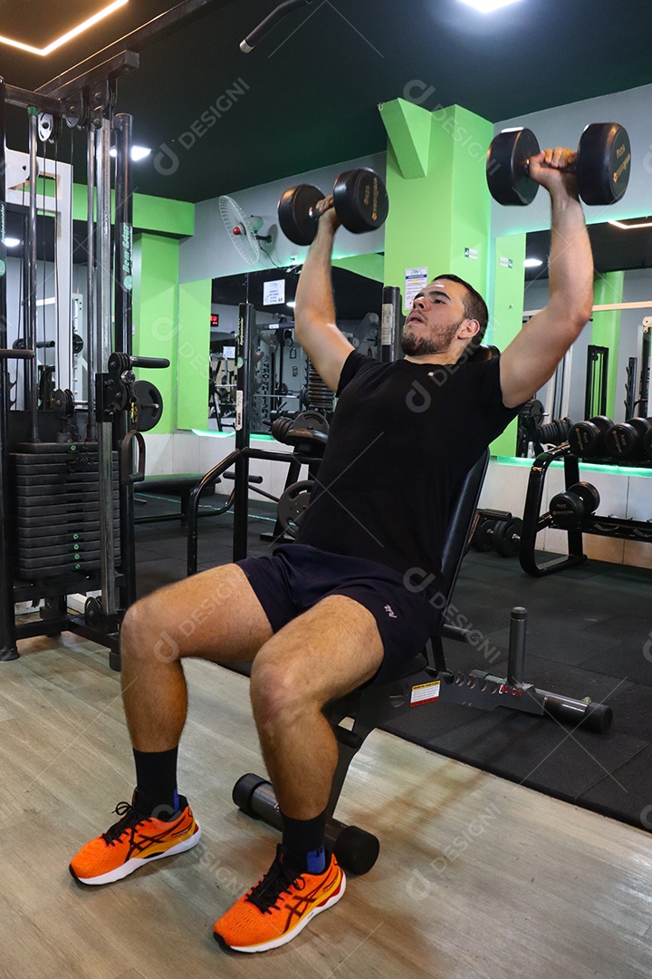 Belo homem fazendo exercicíos sobre uma academia