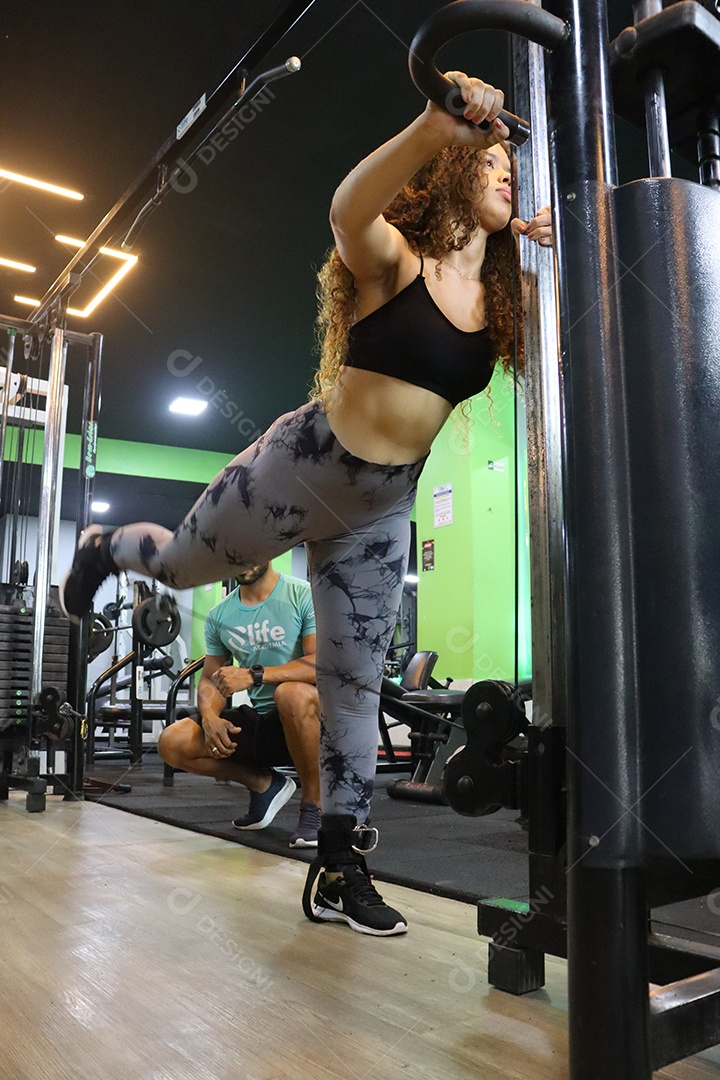 Belo personal trainer ajudando mulher executar exercícios sobre uma academia