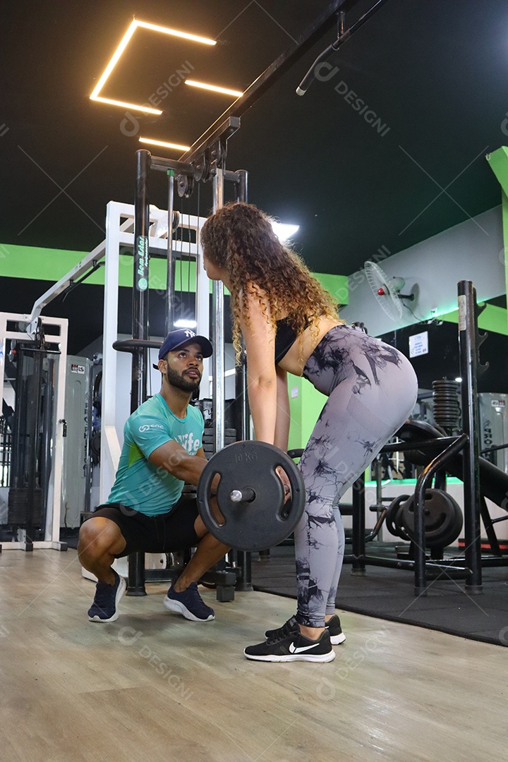 Belo personal trainer ajudando mulher executar exercícios sobre uma academia