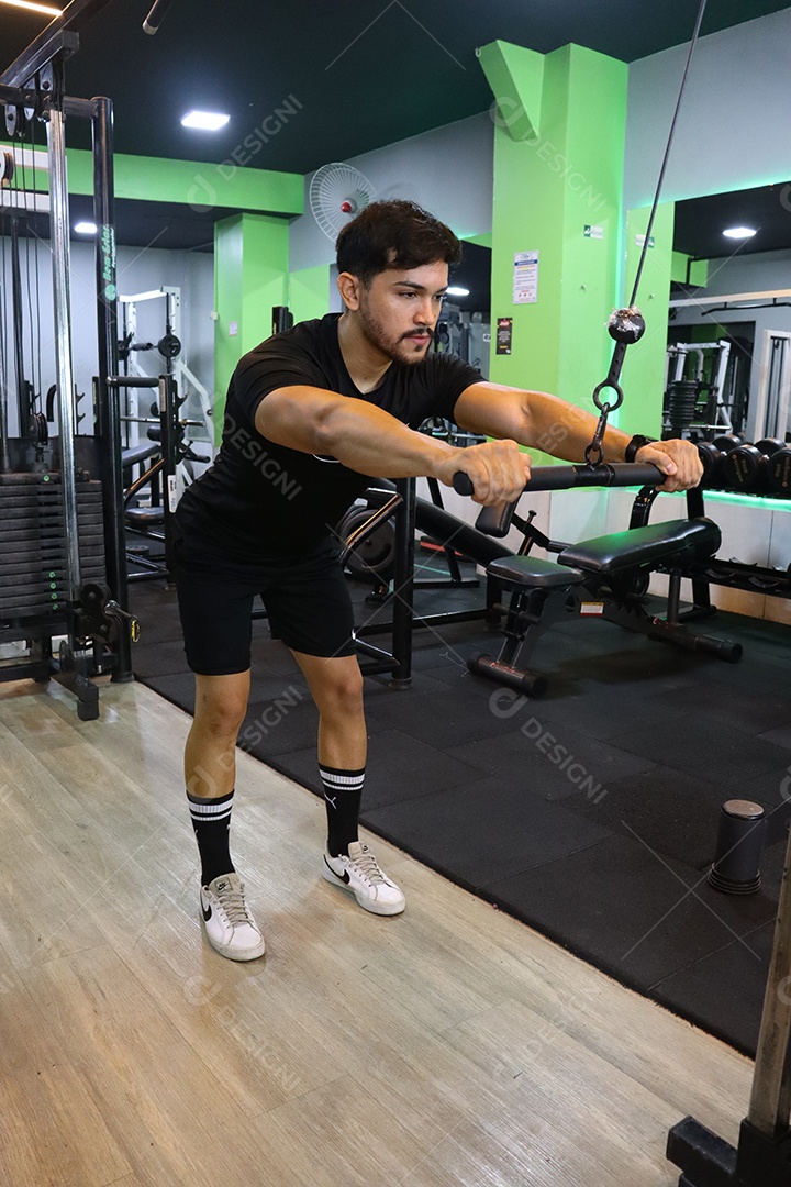 Belo homem fazendo exercicíos sobre uma academia