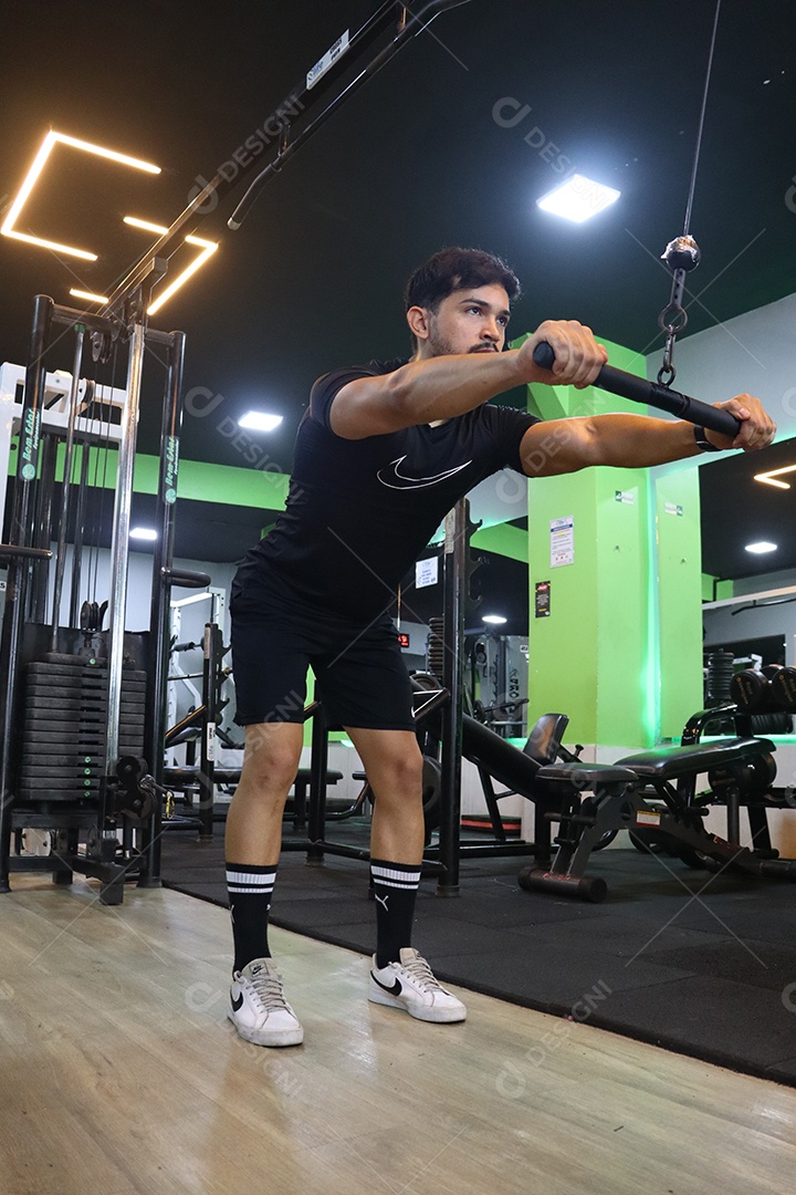 Belo homem fazendo exercicíos sobre uma academia