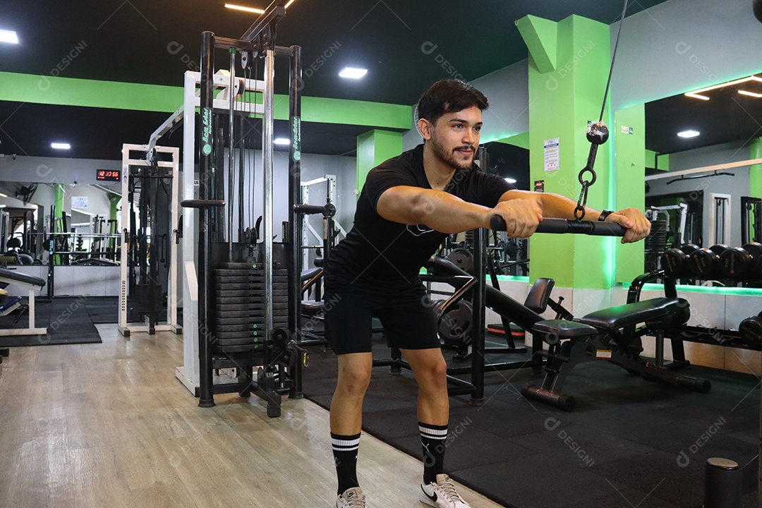 Belo homem fazendo exercicíos sobre uma academia