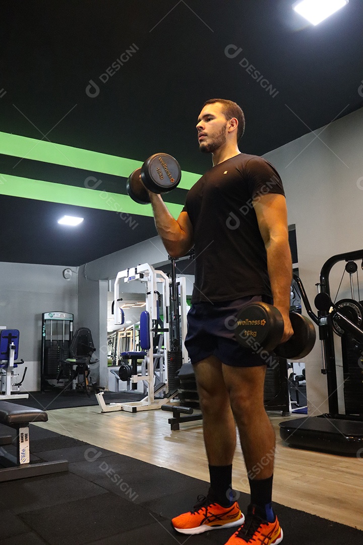 Belo homem fazendo exercicíos sobre uma academia