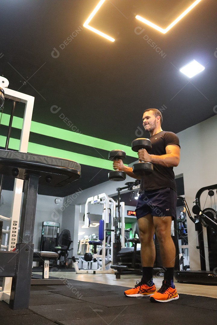 Belo homem fazendo exercicíos sobre uma academia