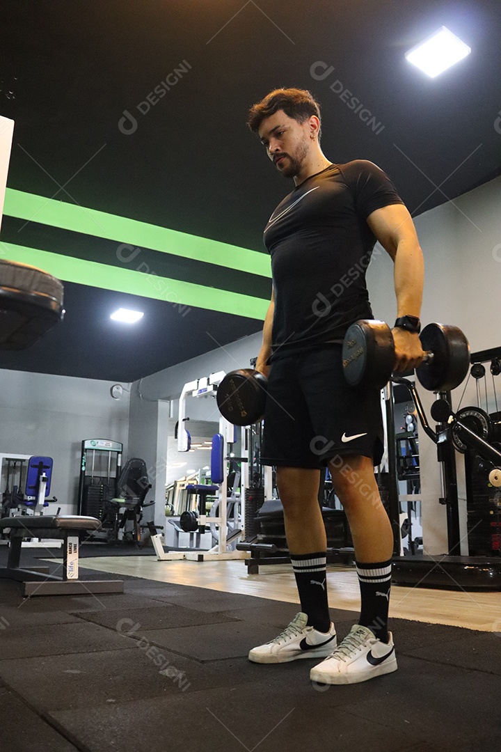 Belo homem fazendo exercicíos sobre uma academia