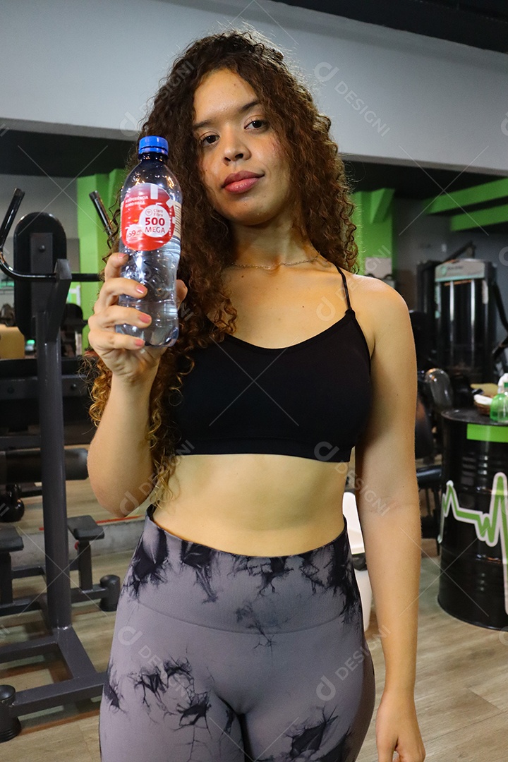 Linda mulher segurando garrafa de água sobre uma academia