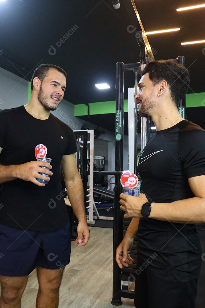 Belos homens segurando copos de água sobre uma academia