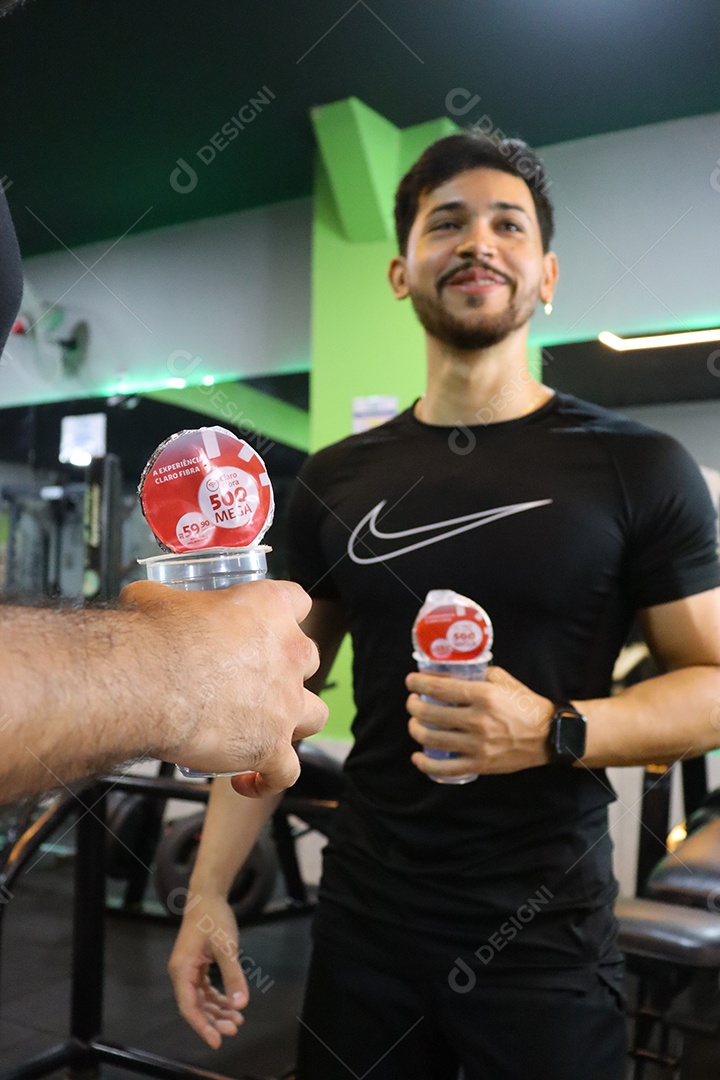 Belos homens segurando copos de água sobre uma academia