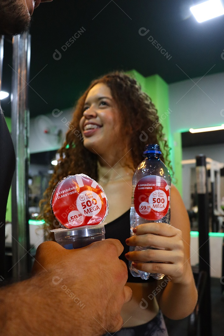 Belo casal segurando copos de água sobre uma academia