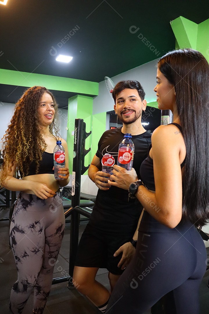 Lindo grupo de amigos segurando garrafas de água sobre uma academia