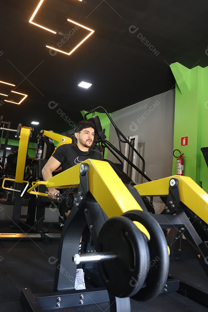 Belo homem fazendo exercicíos sobre uma academia