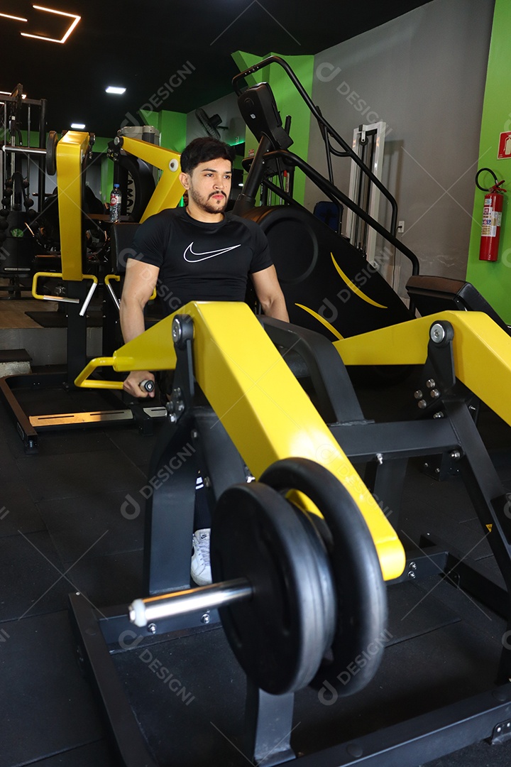 Belo homem fazendo exercicíos sobre uma academia