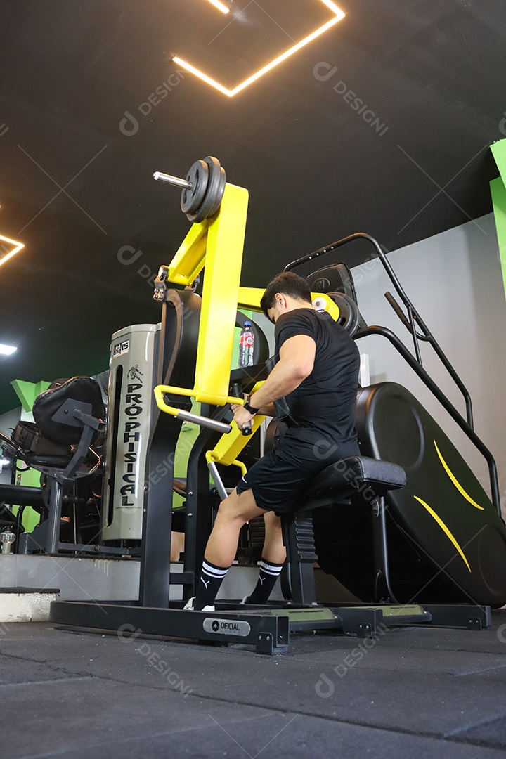 Belo homem fazendo exercicíos sobre uma academia