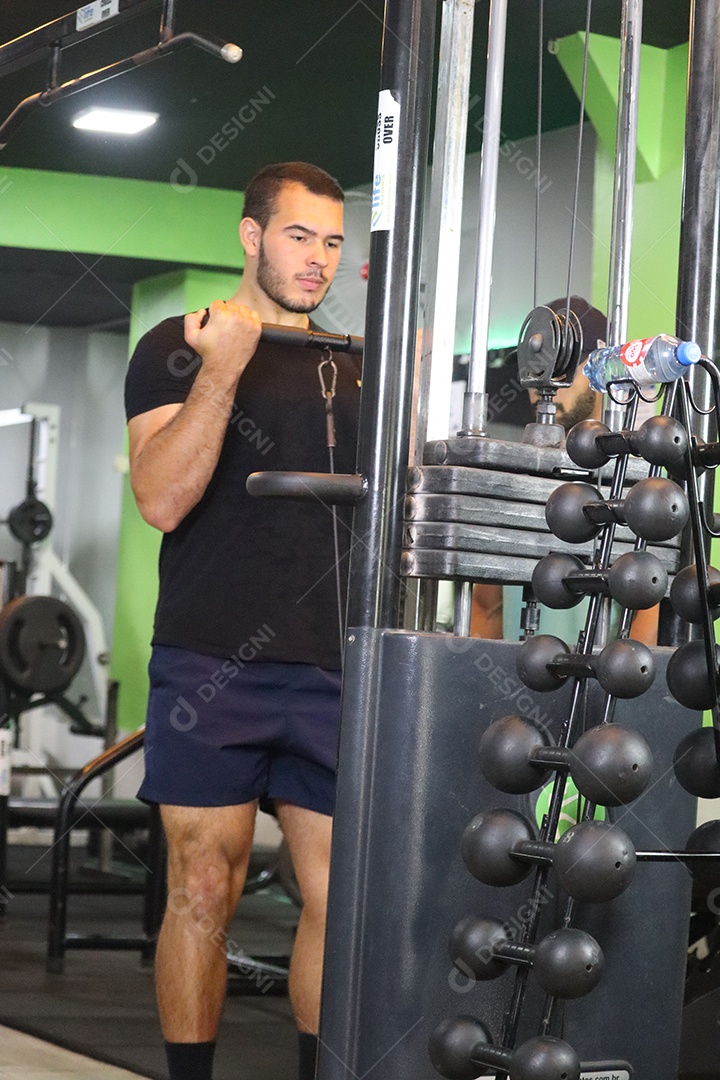 Belo homem fazendo exercicíos sobre uma academia