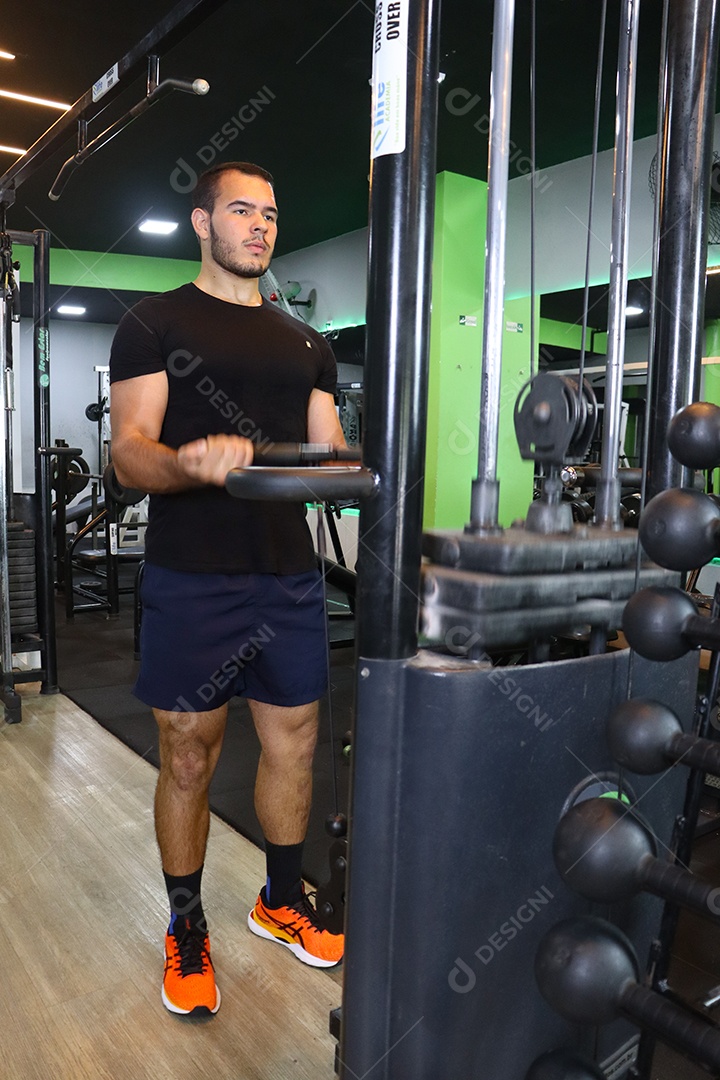 Belo homem fazendo exercicíos sobre uma academia