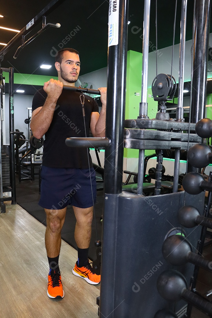 Belo homem fazendo exercicíos sobre uma academia