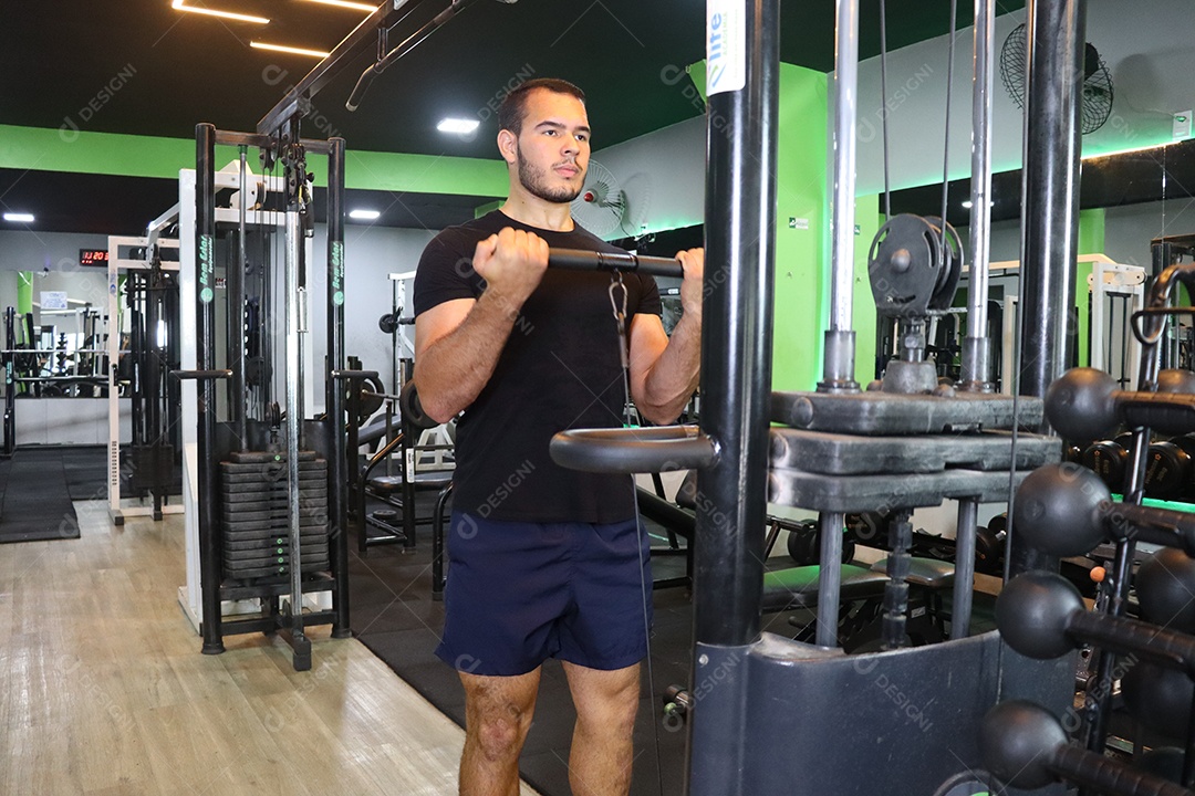 Belo homem fazendo exercicíos sobre uma academia