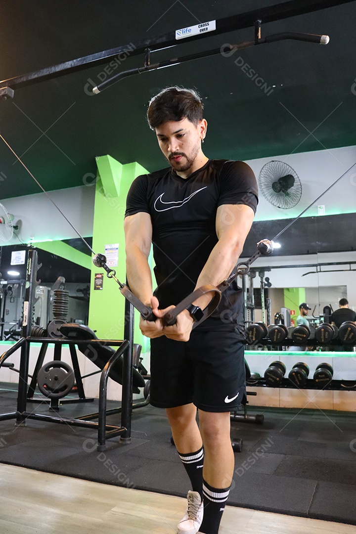 Belo homem fazendo exercicíos sobre uma academia