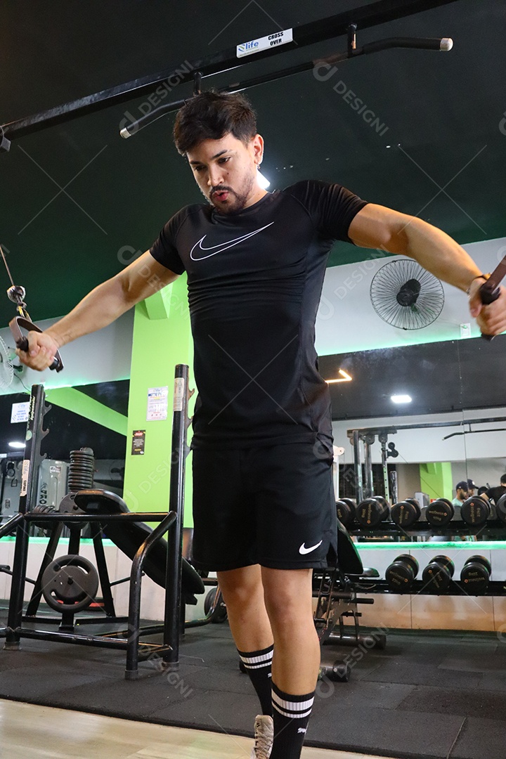 Belo homem fazendo exercicíos sobre uma academia