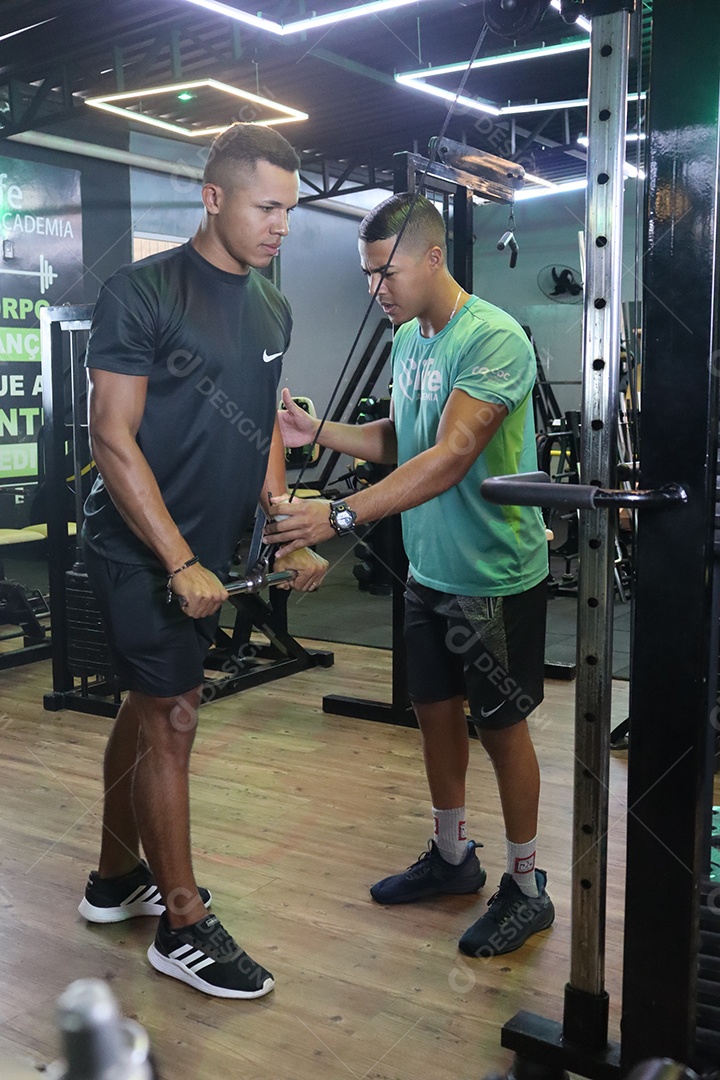 Belo personal trainer ajudando homem executar exercícios sobre uma academia