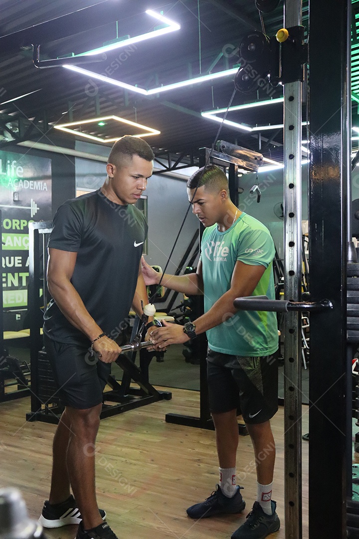 Belo personal trainer ajudando homem executar exercícios sobre uma academia