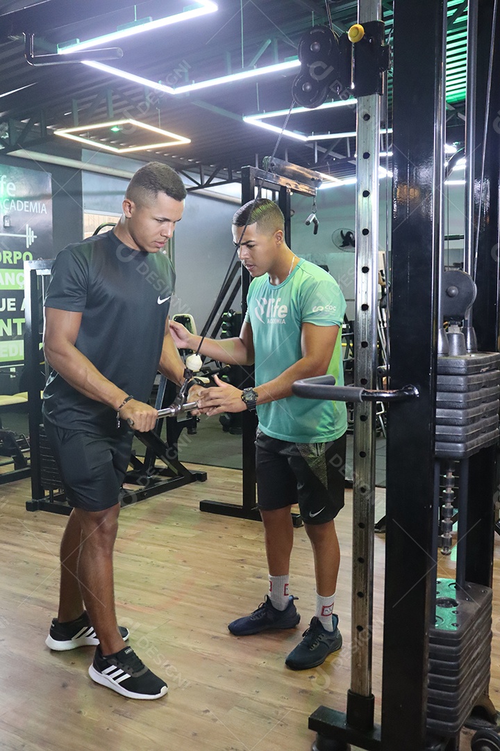 Belo personal trainer ajudando homem executar exercícios sobre uma academia