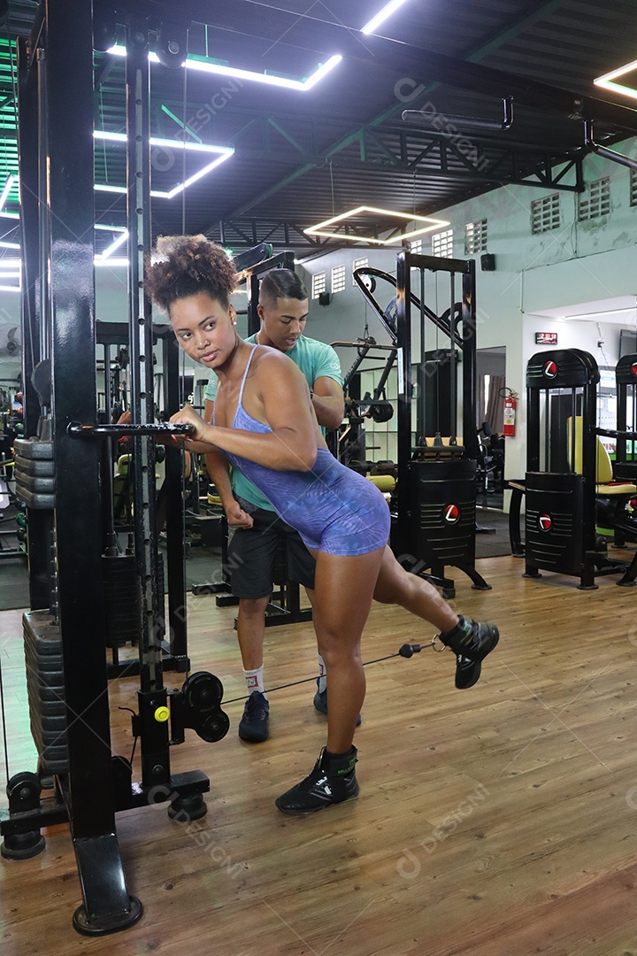 Belo personal trainer ajudando mulher executar exercícios sobre uma academia