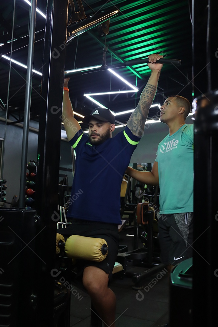 Belo personal trainer ajudando mulher executar exercícios sobre uma academia