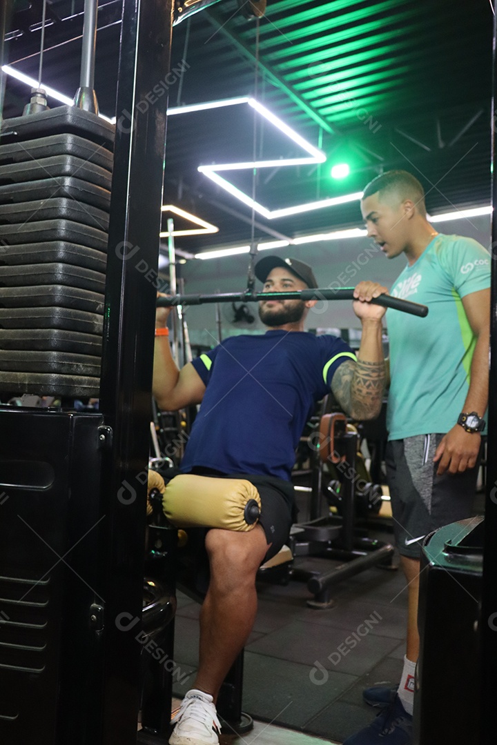 Belo personal trainer ajudando mulher executar exercícios sobre uma academia