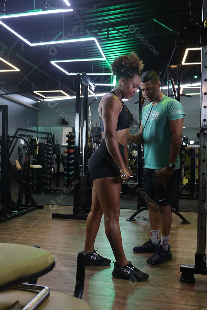 Belo personal trainer ajudando mulher executar exercícios sobre uma academia