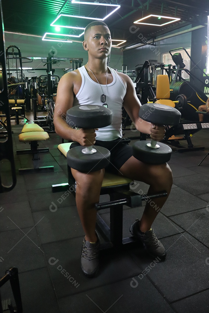 Belo homem fazendo exercicíos sobre uma academia