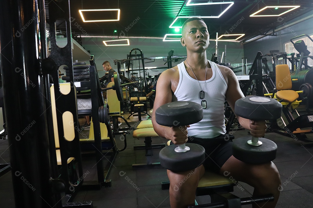 Belo homem fazendo exercicíos sobre uma academia